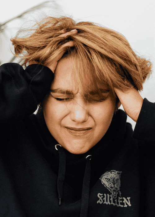 person scrunching eyes closed with hands on head due to disturbing mental imagery