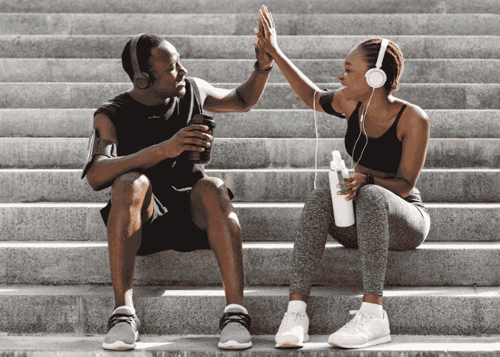man and woman on concrete steps outside after going for a run high-fiving after treatment for stress-related urination