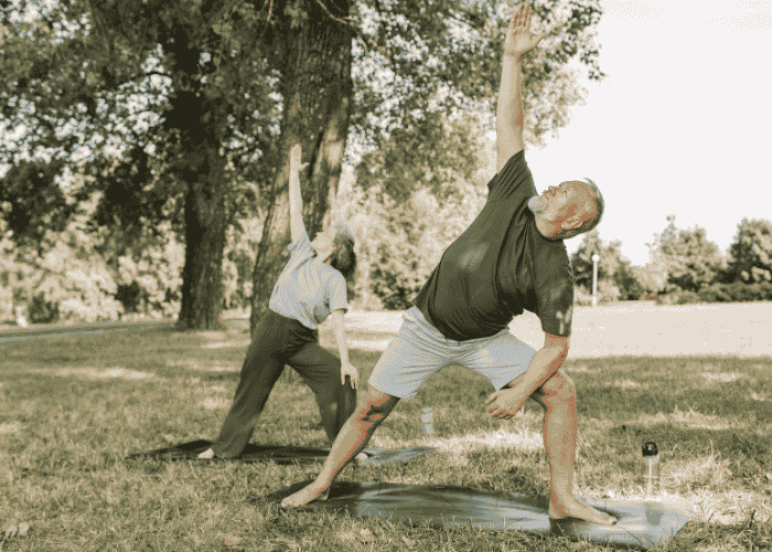 man in park with trees behind him practising yoga after treatment from dizziness under stress
