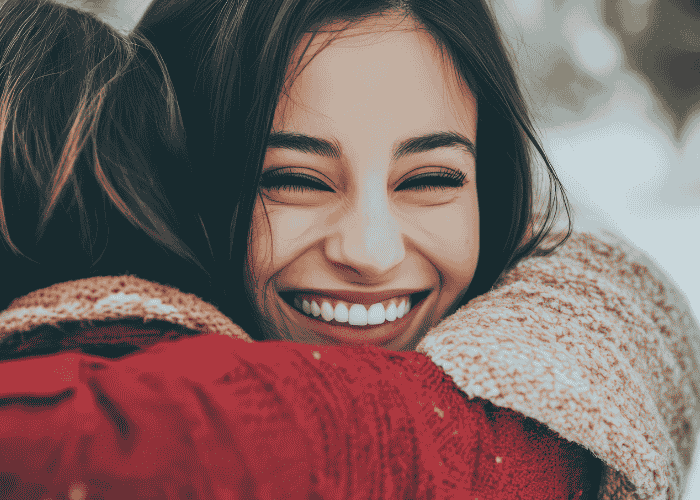 woman hugging friend smiling after receiving support for difficulty expressing emotions