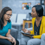 woman sitting on chair next to therapist during CBT session for support with trauma-related emotional flashbacks