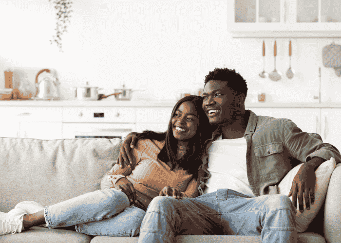 Couple sat on sofa hugging and smiling after support for fear of intimacy in adults.