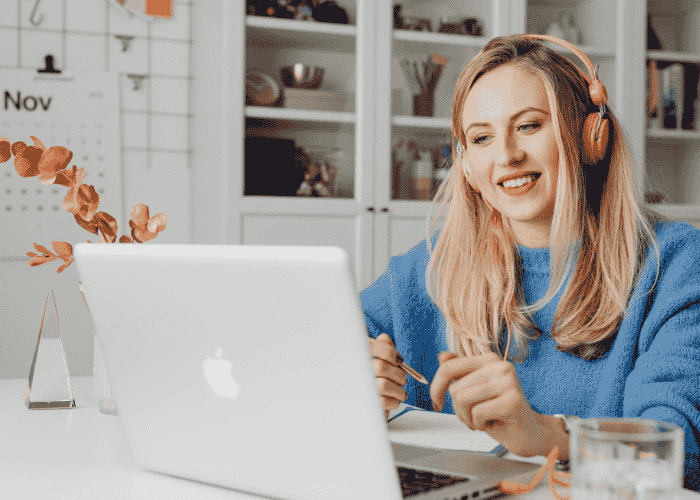 woman working on laptop with headphones on smiling after support for compromised judgement under stress.