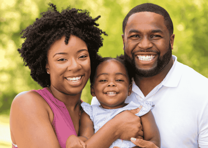woman with husband and young daughter outside smiling after treatment for false memories