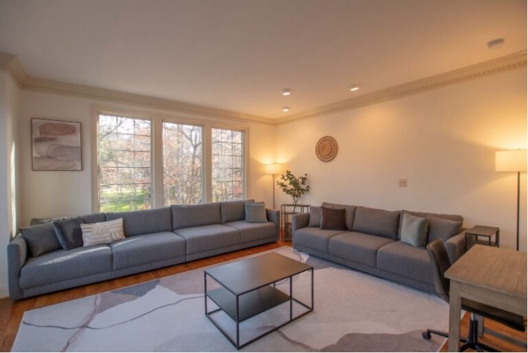 Comfortably lit living room with large grey couches and a coffee table