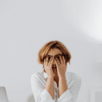 Woman with her hands over her face looking overwhelmed due to catastrophic thinking in adults