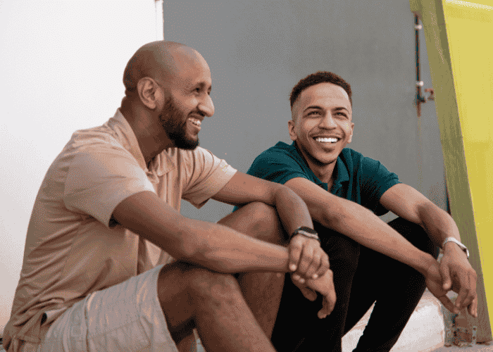 Two men chatting together looking happy after receiving treatment for oversharing in adults