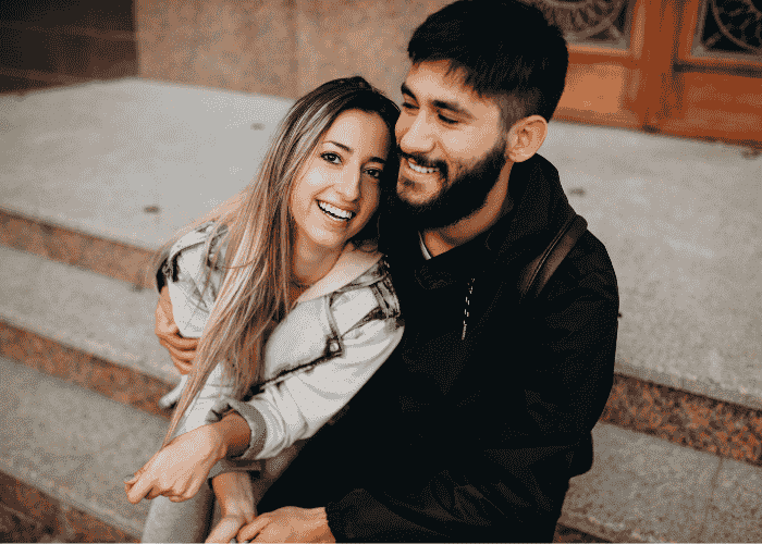 Couple hugging and smiling due to treatment for over-apologizing in adults