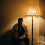 Man sitting beside a lamp because of self-isolation after arguments