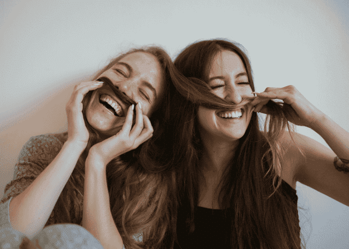 Two women being silly after receiving treatment for feeling like a burden in adulthood