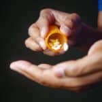 hands holding a pill bottle with small white round pills, ativan for anxiety