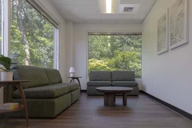 A calming lounge with green and gray sofas in Mission Connection Healthcare facility.