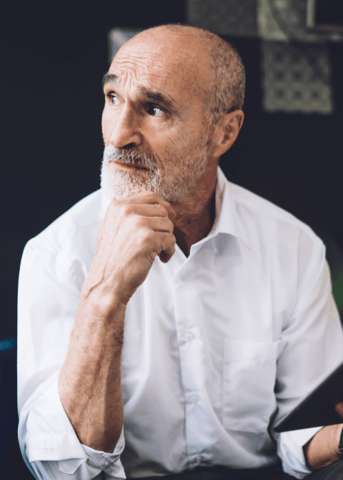 man sitting at table resting chin on hand looking out window worrying about Employers Health Network (EHN) mental health coverage