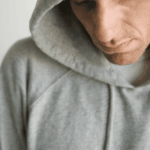 man with hood on head staring at ground worrying about Anthem insurance coverage