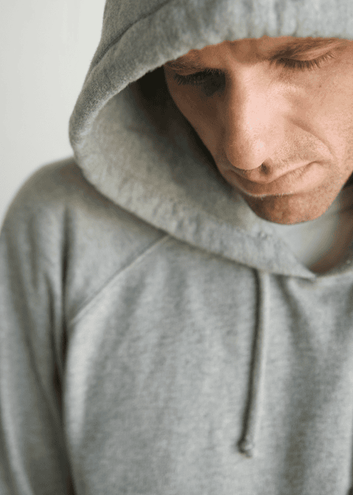 man with hood on head staring at ground worrying about Anthem insurance coverage