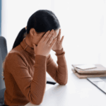 woman at work sitting at desk with hands raised to face experiencing cognitive distortions in adults