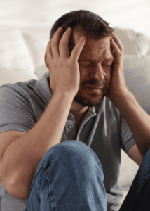 man sitting on floor by sofa with knees up and hands raised to head needing support with most common cognitive distortions in adults
