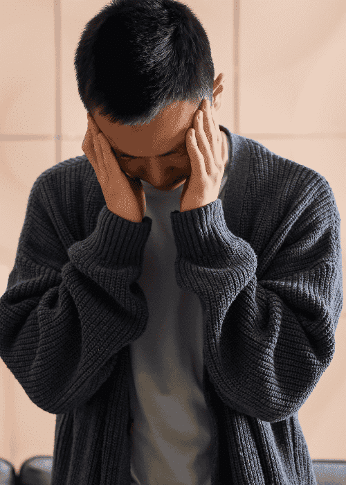 Man standing in kitchen leaning against counter top with hands on head experiencing depression and distorted thinking patterns in adults