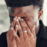 man standing with hands over face needing support with emotional reasoning