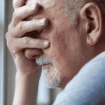 man by window with hand over face, feeling worried about Halcyon Behavioral Health Insurance