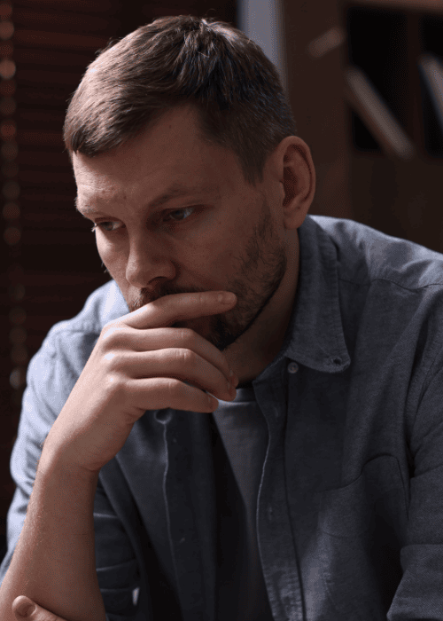 man sitting alone with hand over mouth worrying about HMC HealthWorks mental health insurance coverage