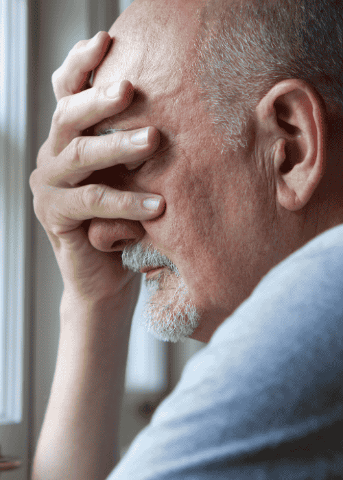 Man with hand over face needing support using insurance to cover mental health treatment