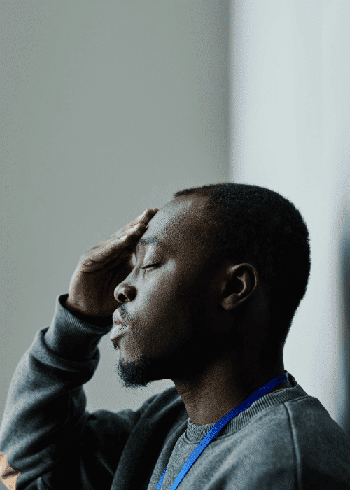 Man standing against wall with hand on head worrying about seeking support from Aetna mental health insurance