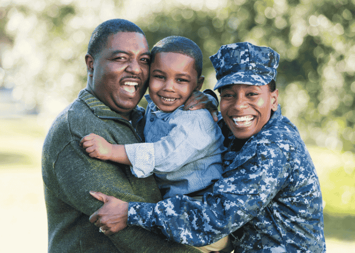 veteran with husband and young son in park smiling and hugging after seeking support with TRICARE mental health coverage