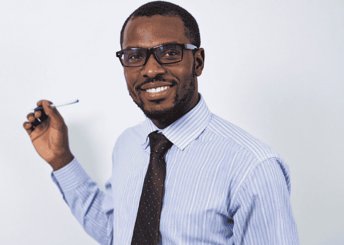 man standing in front of whiteboard in office smiling confidently after seeking support with Carelon Behavioral Health Insurance