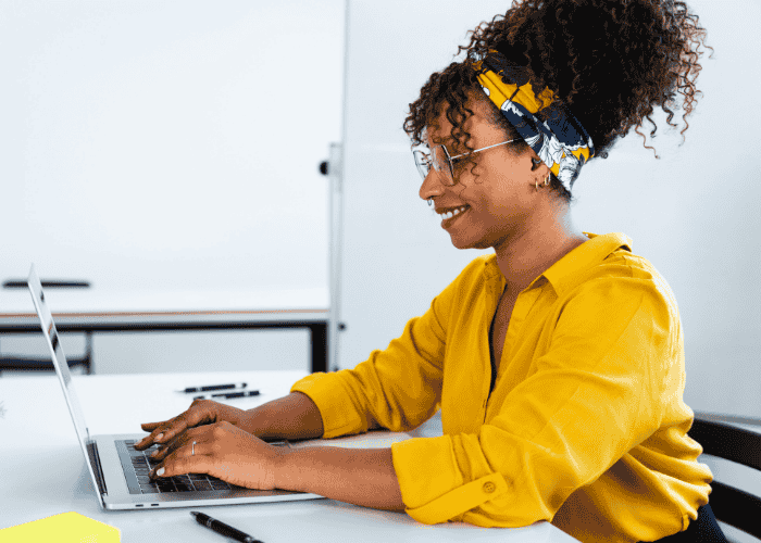 Woman sitting at desk typing on laptop smiling after seeking support for most common cognitive distortions in adults
