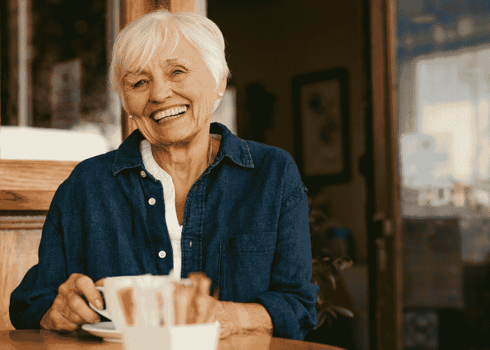 Woman sitting in cafe drinking tea and smiling after seeking support with Aetna mental health insurance