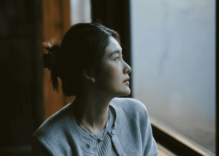 Woman looking out of the window looking unhappy due to insurance barriers to mental health care in Virginia