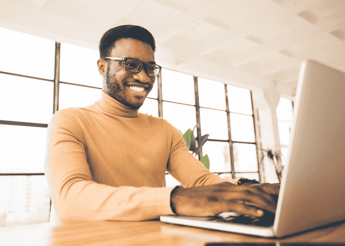 Man using laptop smiling after searching Google’s most asked mental health questions in 2025