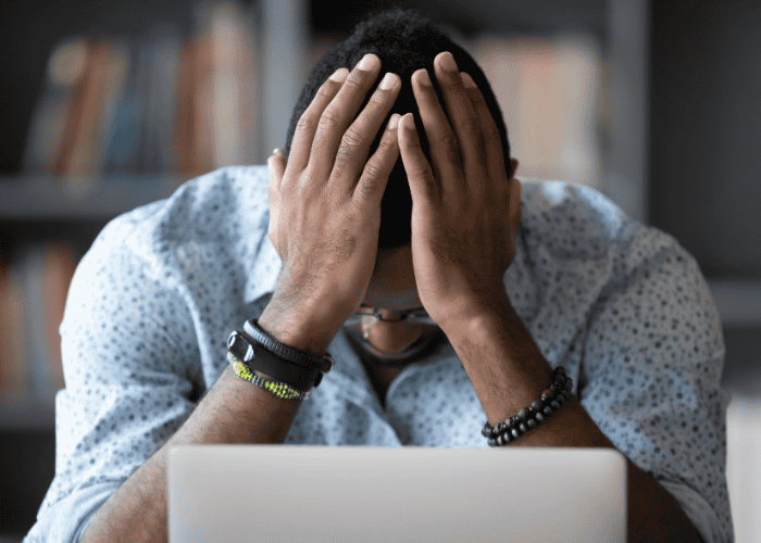 Man sitting at laptop with head in hands needing more information on how everyday choices affect your mental health