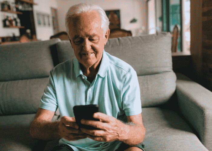 Man sitting on sofa looking at phone smiling after seeking support with how to use mental health apps wisely