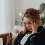 Woman looking distressed with her hands on her head, wondering how cognitive distortions shape thinking and behavior