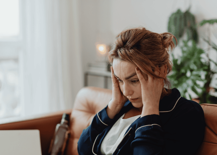 Woman looking distressed with her hands on her head, wondering how cognitive distortions shape thinking and behavior