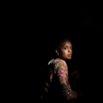 Woman in pitch black with light shining on her face, showing experience of trauma and cognitive distortions