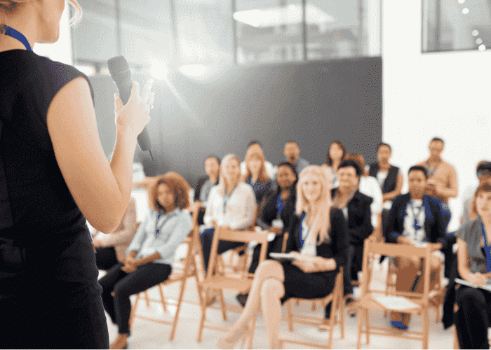 Woman speaking in front of a crowd after receiving treatment for performance anxiety and negative thought loops