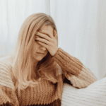 Woman with hand over her face struggling due to barriers to mental health care