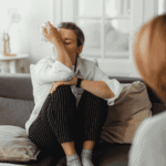 Woman sitting on couch with arm over her face during a therapy session