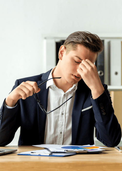 Man sitting at desk with hand on face needing support with mental health documentation for HR