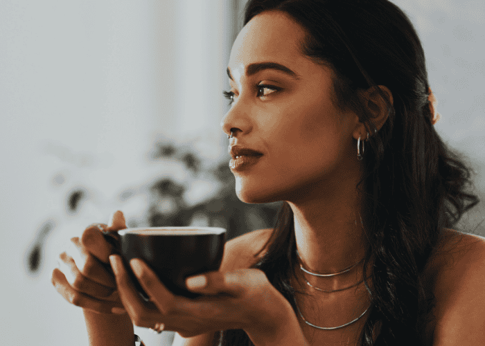 Woman drinking coffee looking calm after support with people pleasing