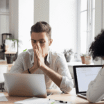 Man looking at laptop with his hands over mouth, experiencing headline stress disorder