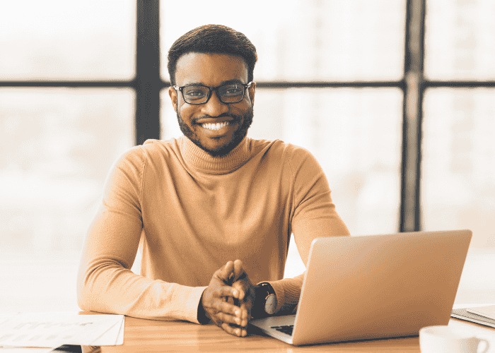 Man sitting at desk in office smiling after seeking support from Employee Assistance Programs