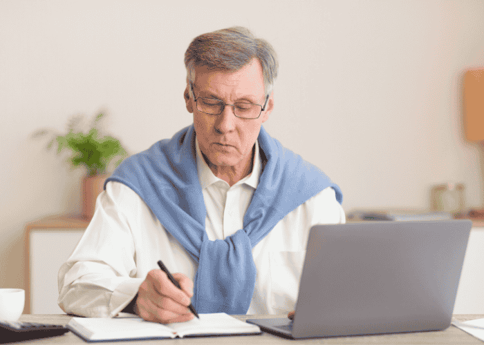 Man sitting at desk working looking calm after seeking support with managing treatment while working full-time