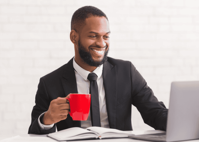 Man working and desk holding mug smiling after support for mental health documentation for HR