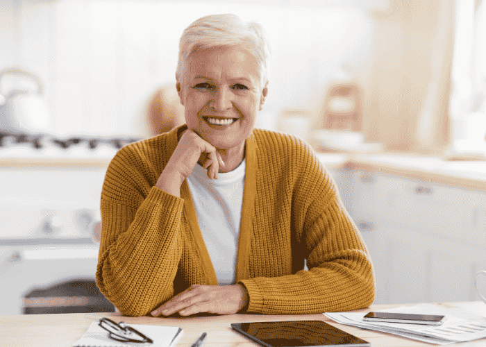 Woman sitting at home in kitchen smiling after considering short-term disability for mental health treatment