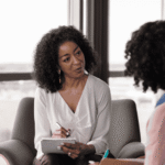 Female therapist in therapy session holding clipboard and pen supporting client with legal protections for mental health patients