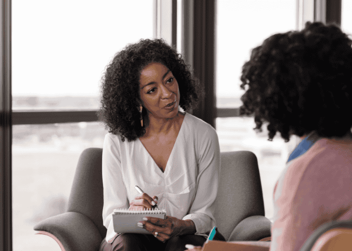 Female therapist in therapy session holding clipboard and pen supporting client with legal protections for mental health patients